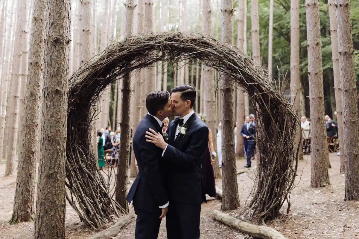 Newlywed kissing gay couple at the pine grove, a natural cathedral at Roxbury Barn & Estate and an LGBTQ-friendly wedding venue in New York