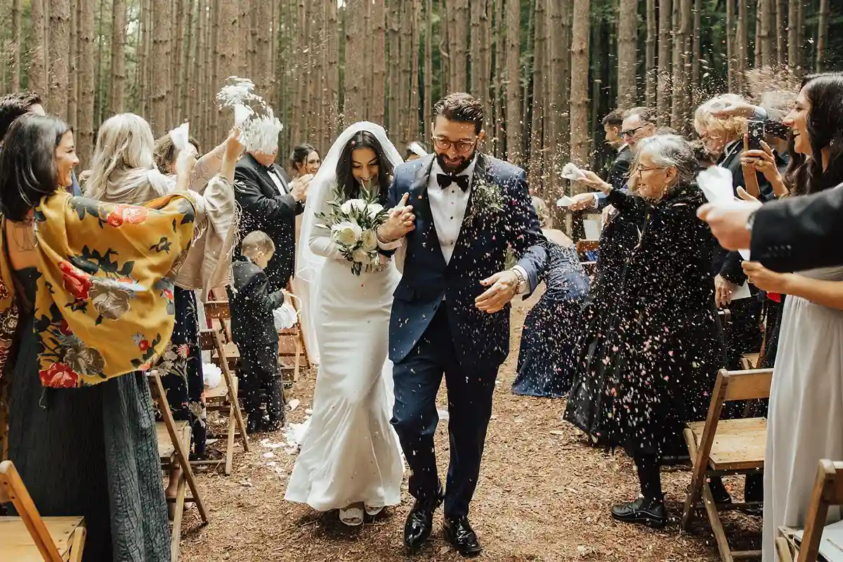 Newlywed couple gets showered in toss in the aisle at an outdoor forest wedding ceremony in upstate New York